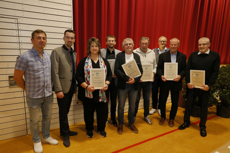 Menschen stehen vor einem roten Vorhang und zeigen ihre erhaltenen Zertifikate.